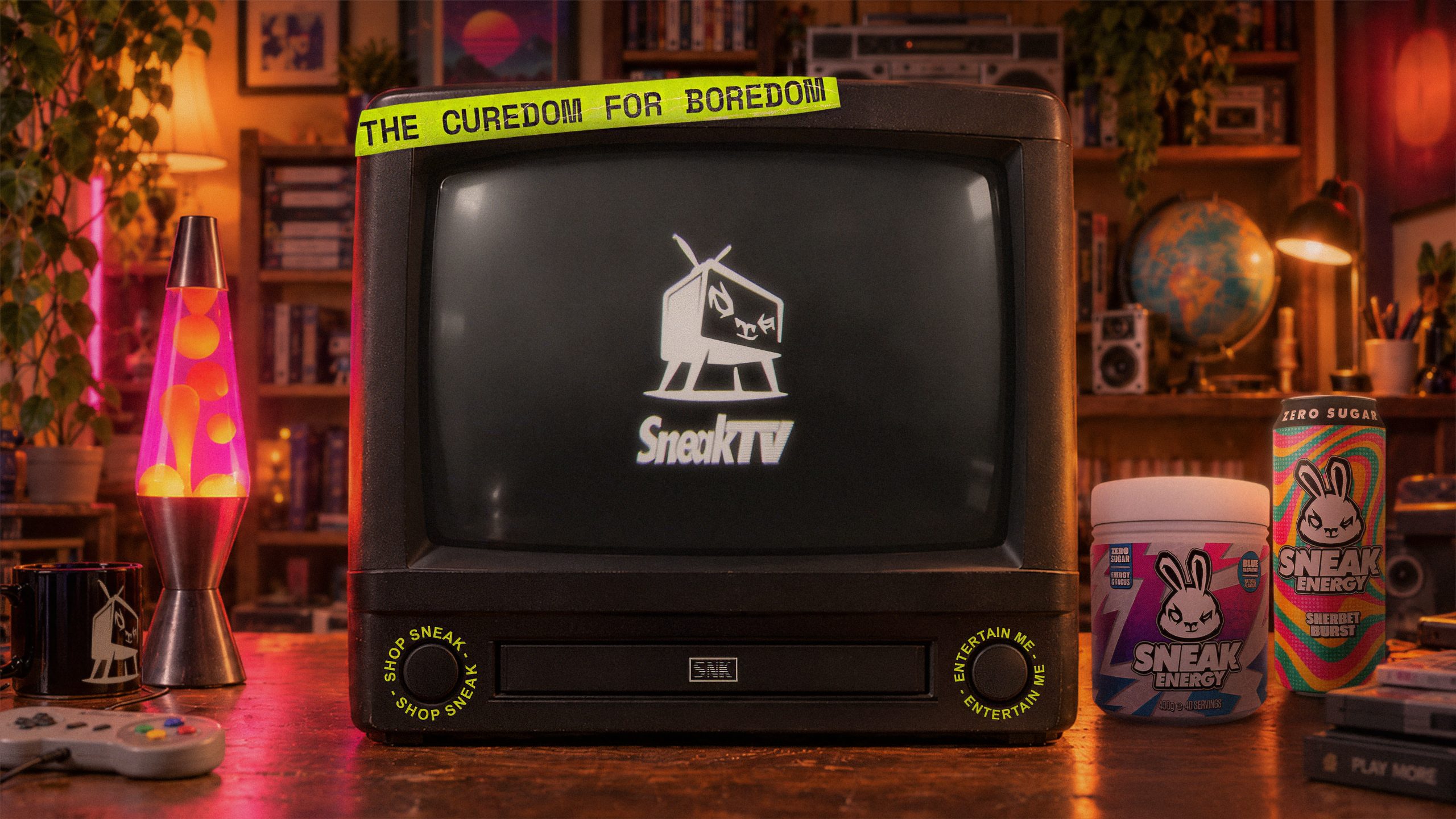 A retro CRT television on a desk with Sneak Energy tubs and cans, taped with 'The Curedom for Boredom'